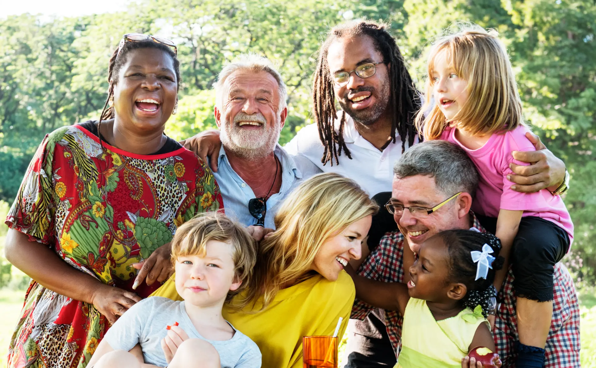 A group of people of different ages and backgrounds gathered together outdoors, smiling and enjoying each other's company